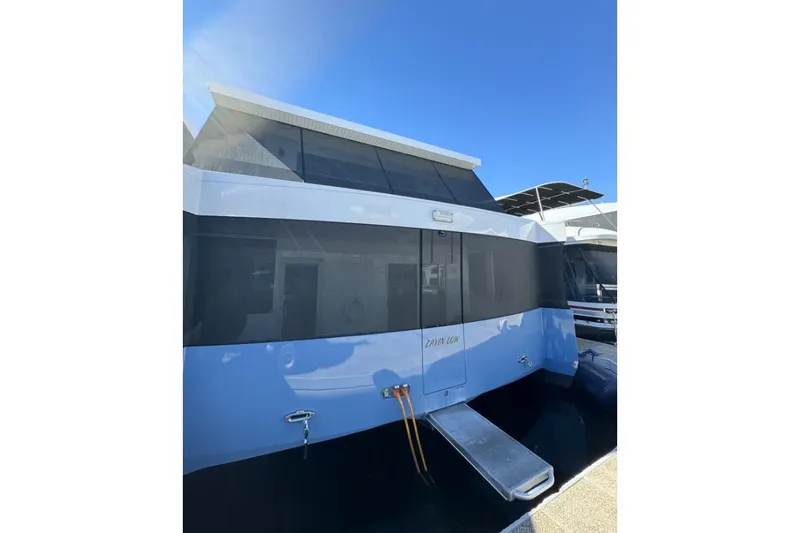 Slide: The Image of 2022 Adonia Layin' Low houseboat with sleek design, docked under clear blue sky. - 6