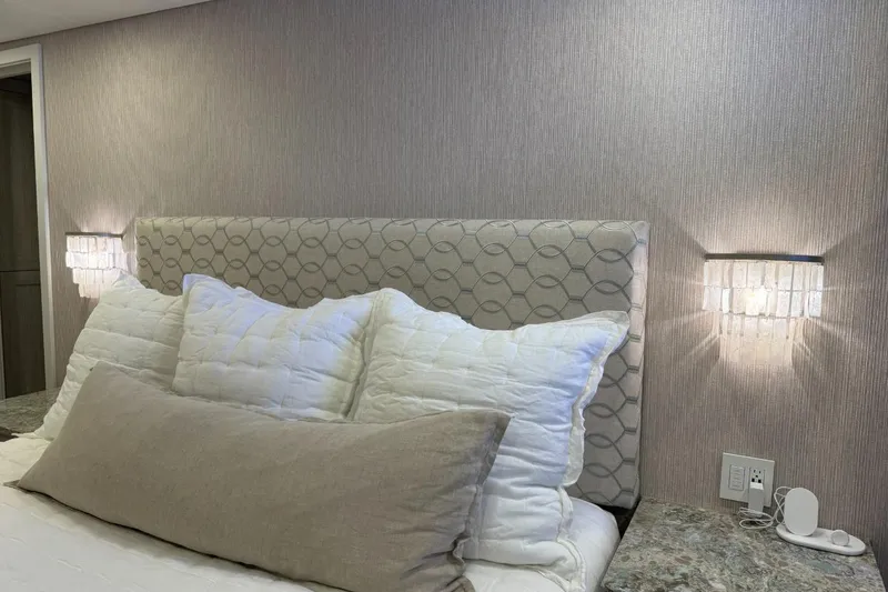 Slide: The Image of Elegant bedroom with plush pillows, geometric headboard, and modern wall sconces in Adonia Layin' Low 2022. - 8