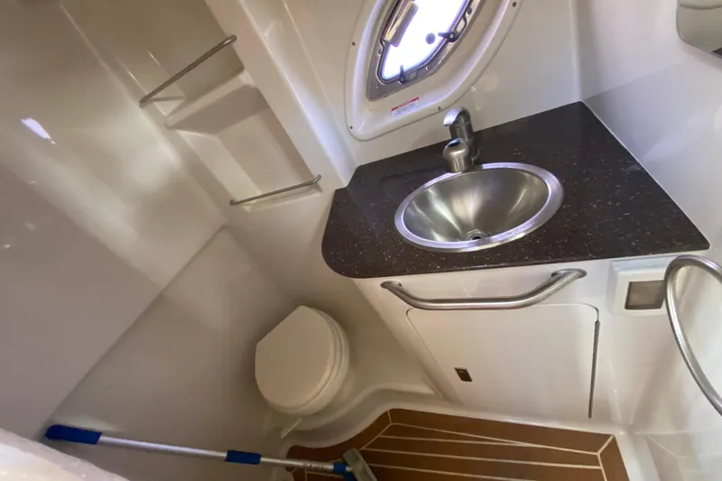 Slide: The Image of 2012 Sea Ray 330 Sundancer bathroom with sink, toilet, and porthole window. - 28