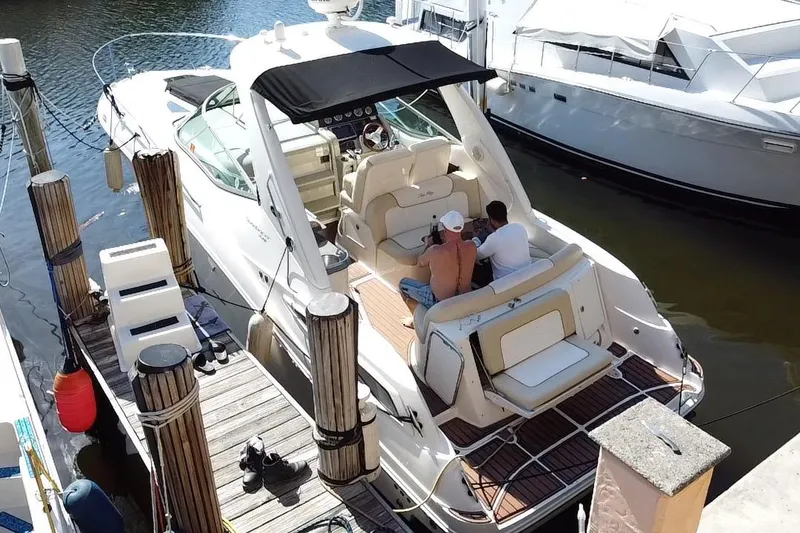 Slide: The Image of 2012 Sea Ray 330 Sundancer docked with two people relaxing onboard. - 36