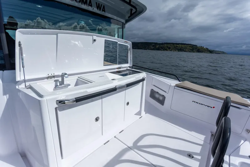 Slide: The Image of 2022 Axopar 37 XC Cross Cabin boat with outdoor sink and storage, on a scenic waterway. - 22