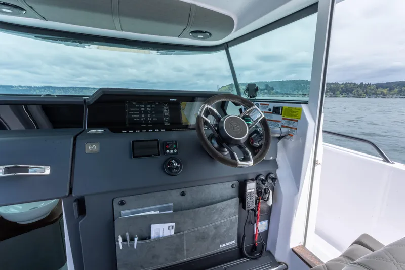 Slide: The Image of 2022 Axopar 37 XC Cross Cabin helm with modern controls and scenic water view. - 31