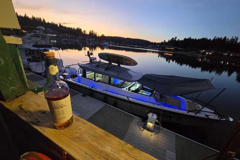 Slide: The Image of 2022 Axopar 37 XC Cross Cabin docked at sunset with a bottle of whiskey nearby. - 41