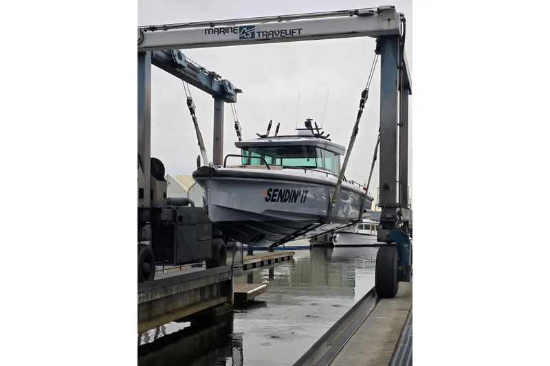 Slide: The Image of 2022 Axopar 37 XC Cross Cabin boat being lifted by a Marine Travelift at a dock. - 42