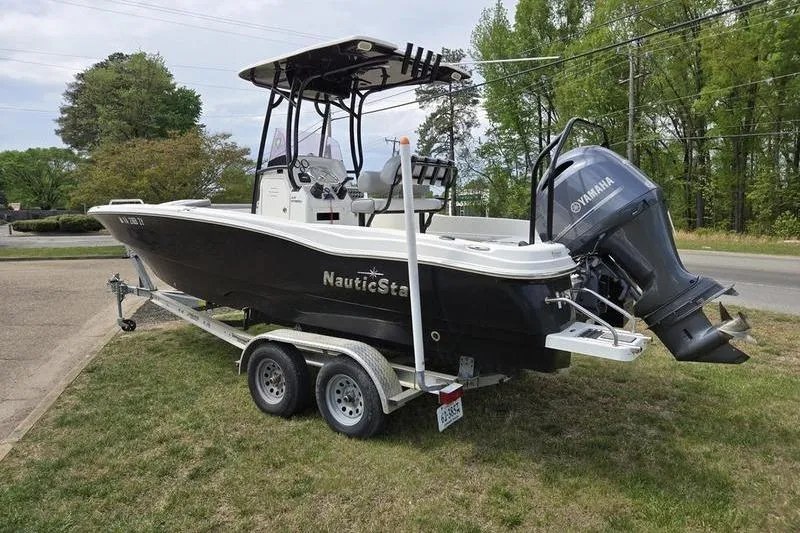 Slide: The Image of 2021 NauticStar 231 Hybrid boat on trailer with Yamaha outboard motor, parked on grass. - 12