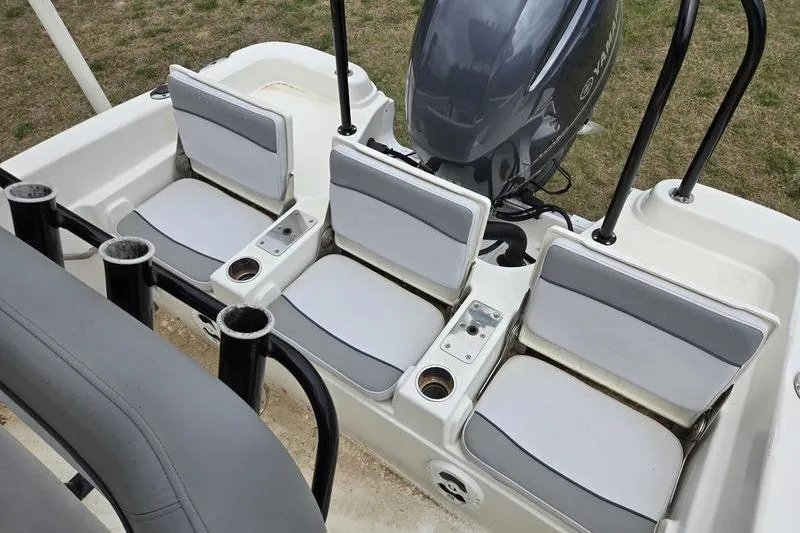 Slide: The Image of 2021 NauticStar 231 Hybrid boat seating area with rod holders and engine view. - 15