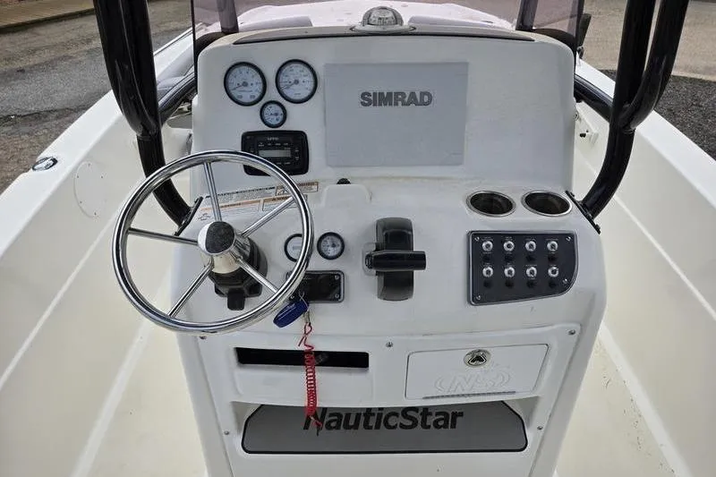 Slide: The Image of 2021 NauticStar 231 Hybrid boat dashboard with steering wheel and Simrad electronics. - 17