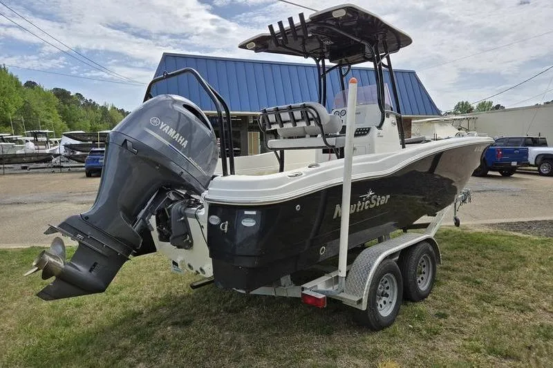 Slide: The Image of 2021 NauticStar 231 Hybrid boat with Yamaha engine on a trailer, parked outdoors. - 2