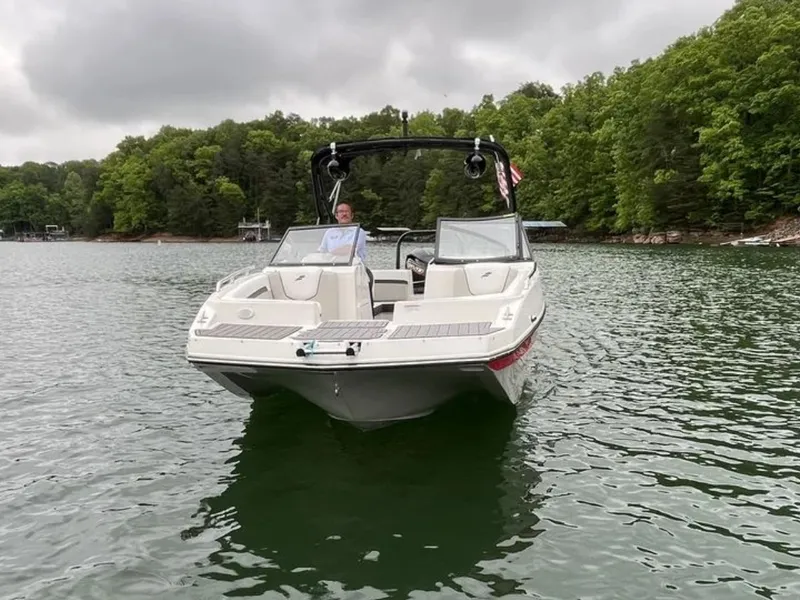 Slide: The Image of A 2025 Starcraft SVX OB 230 DC OB boat on a calm lake, surrounded by trees. - 3