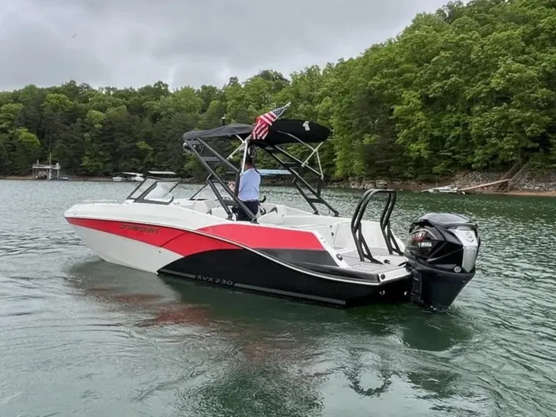 Slide: The Image of A 2025 Starcraft SVX OB 230 DC OB boat on a calm lake with wooded shores. - 5