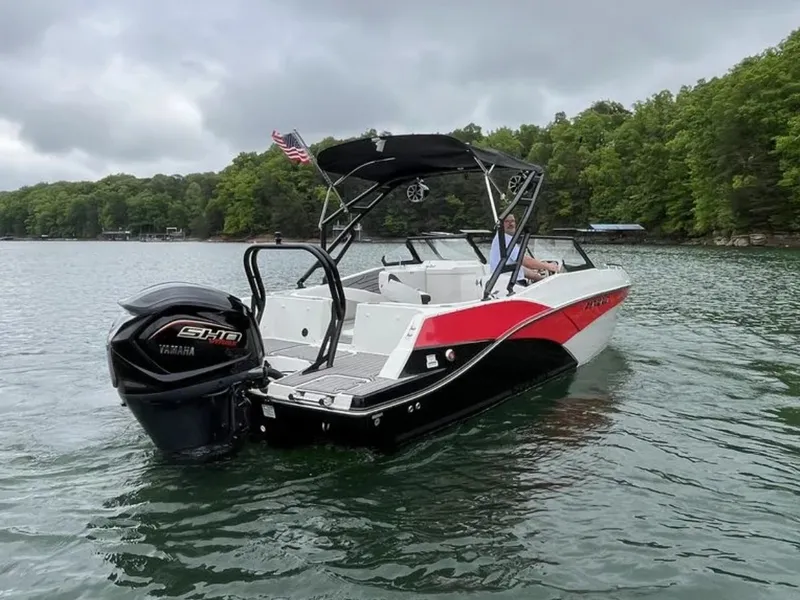 Slide: The Image of A 2025 Starcraft SVX OB 230 DC OB boat on a calm lake with wooded shoreline. - 16