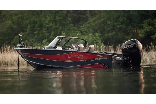 The Image of 2026 Lund 1875 Crossover XS boat on calm water, surrounded by lush greenery. - 1