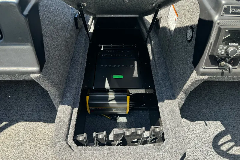 Slide: The Image of 2026 Lund 1875 Crossover XS boat interior showing storage compartment and electronic equipment. - 19