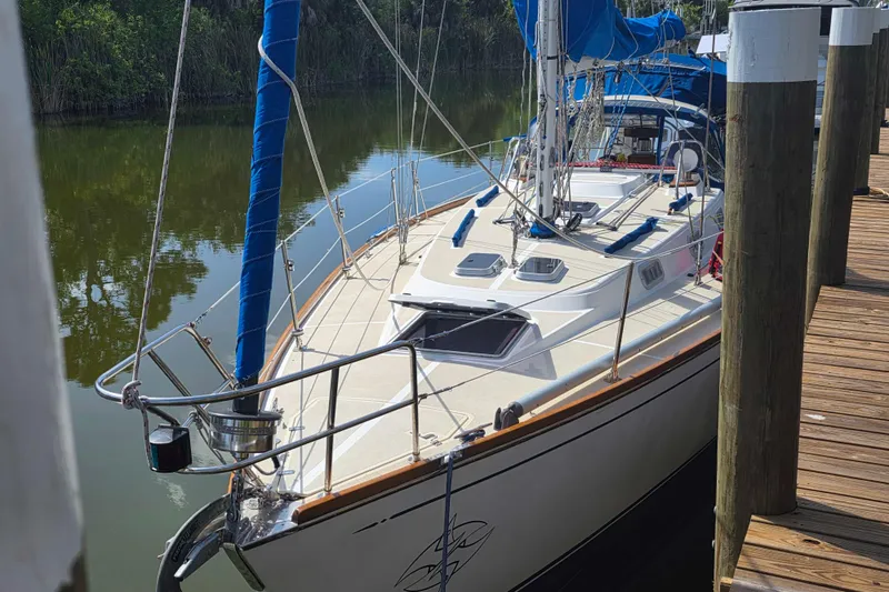 The Image of Sailboat Tartan 372, 1990 model, docked on a calm river with blue sails. - 0