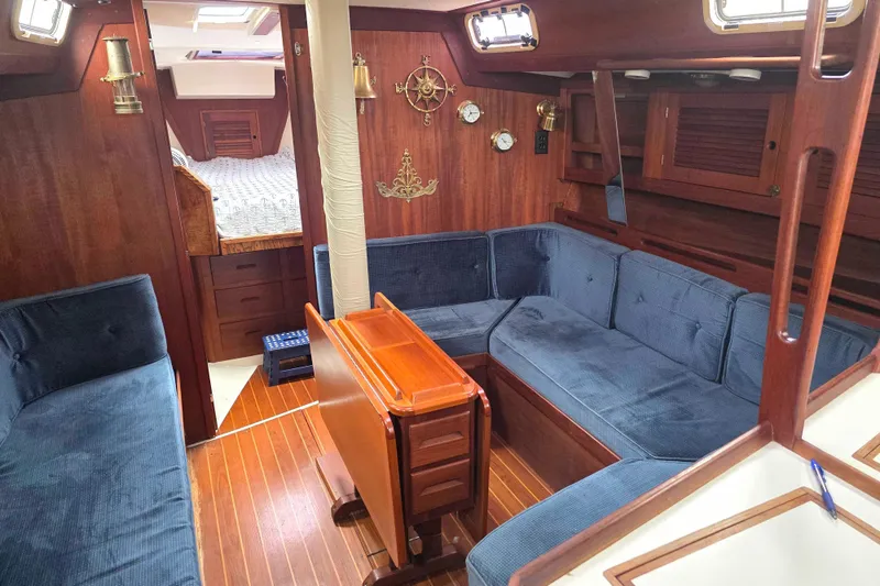 Slide: The Image of Interior of a 1990 Tartan 372 sailboat with blue seating and wooden accents. - 14