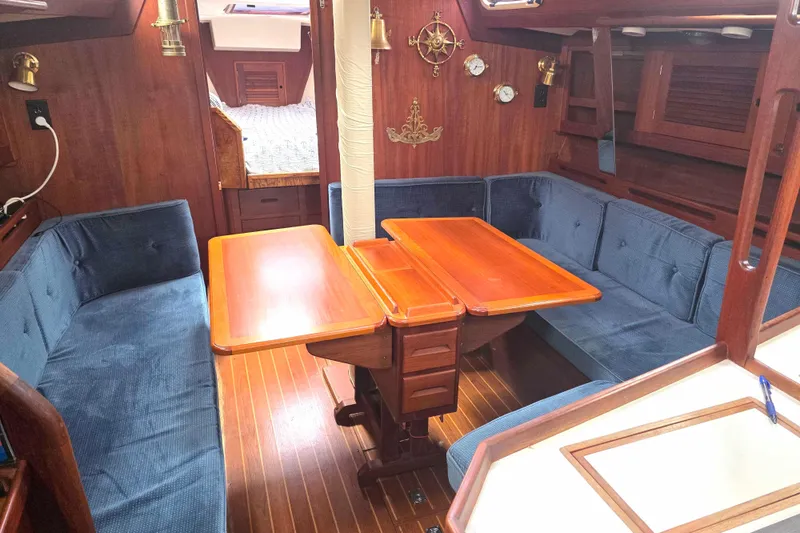 Slide: The Image of Interior of a 1990 Tartan 372 sailboat with wooden table and blue seating. - 15