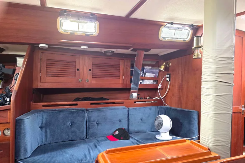 Slide: The Image of Interior of a 1990 Tartan 372 sailboat with wooden cabinetry and blue seating. - 17