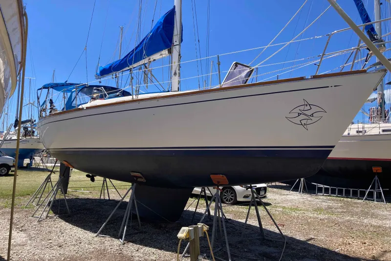 Slide: The Image of Sailboat on stands, Tartan 372 model from 1990, with blue sails and fish emblem. - 2