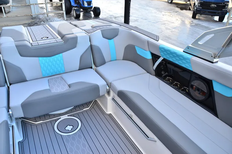 Slide: The Image of 2023 MasterCraft XT22 T boat interior with gray and blue seating, cup holders, and speaker system. - 13