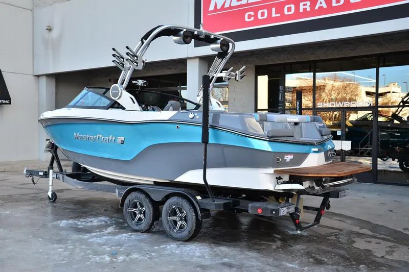 Slide: The Image of 2023 MasterCraft XT22 T boat on trailer outside showroom, featuring sleek blue design. - 4