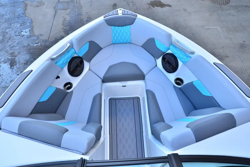 Slide: The Image of 2023 MasterCraft XT22 T boat interior with gray and blue seating, cup holders, and speakers. - 8