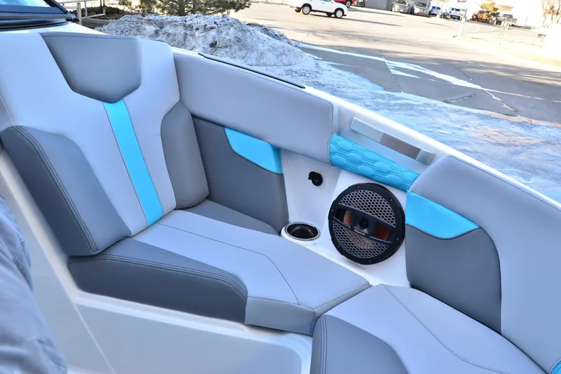 Slide: The Image of 2023 MasterCraft XT22 T boat interior with gray and blue seating, speaker, and cup holder. - 9
