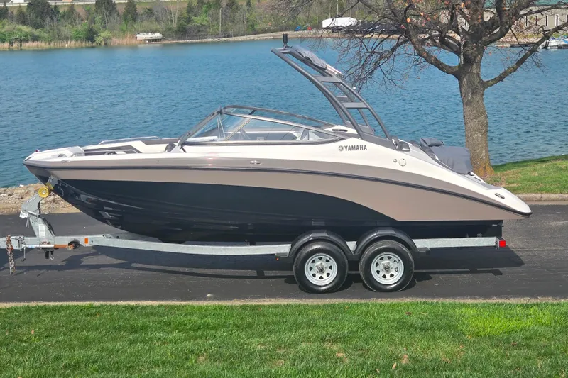 The Image of 2022 Yamaha AR210 boat on trailer by a lake, showcasing sleek design and modern features. - 0