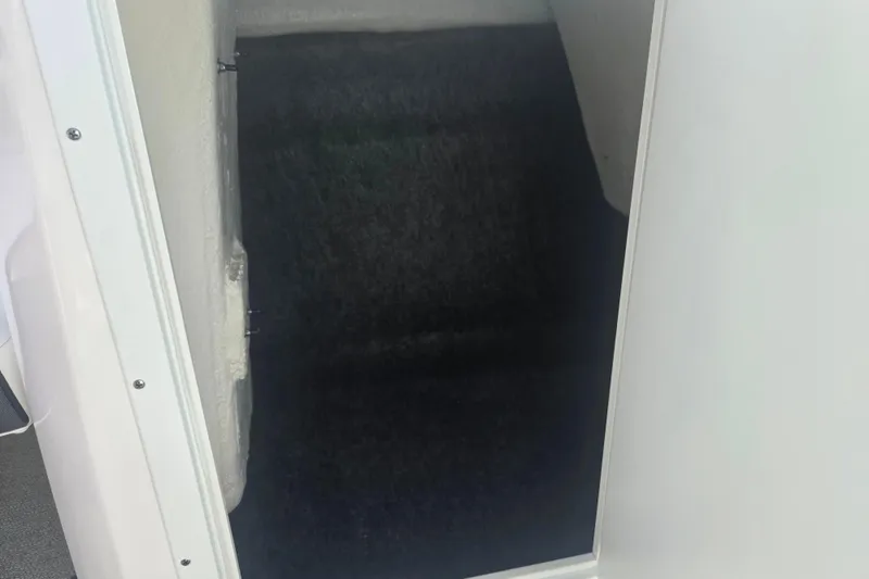 Slide: The Image of Interior storage compartment of 2022 Yamaha AR210 boat, featuring dark carpeted flooring. - 14