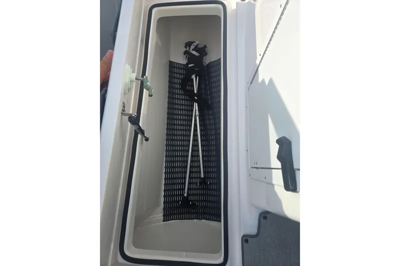 Slide: The Image of Storage compartment in a 2022 Yamaha AR210 boat, featuring a black mat and equipment. - 16