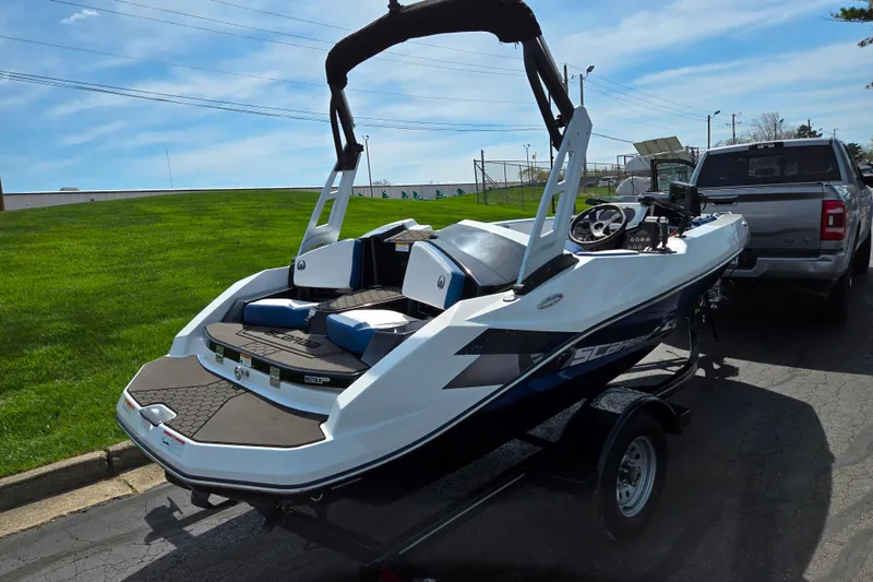 Slide: The Image of 2021 Scarab 165 ID boat on trailer, parked beside a truck on a sunny day. - 3