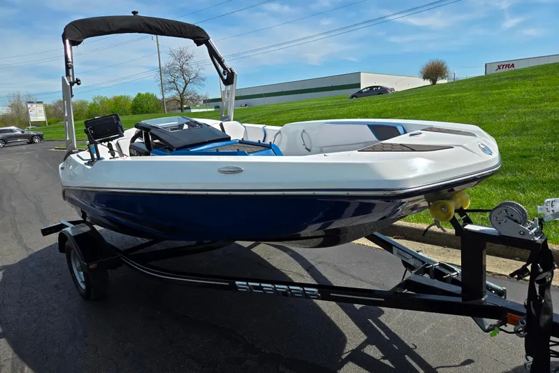 Slide: The Image of 2021 Scarab 165 ID boat on trailer, blue and white design, parked outdoors. - 5