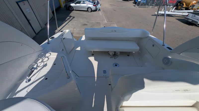Slide: The Image of 2004 Sea Ray 280 Sundancer boat deck with seating and cup holders, parked in a marina. - 11