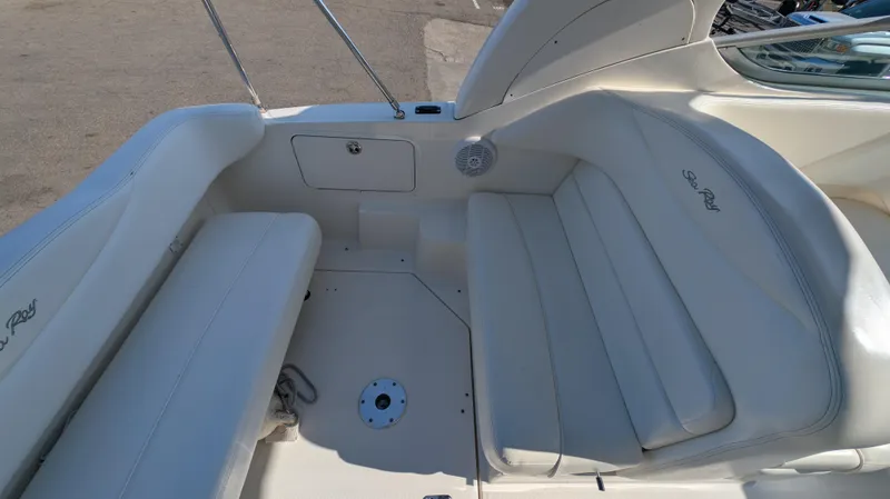 Slide: The Image of 2004 Sea Ray 280 Sundancer boat interior with white seating and storage compartment. - 12
