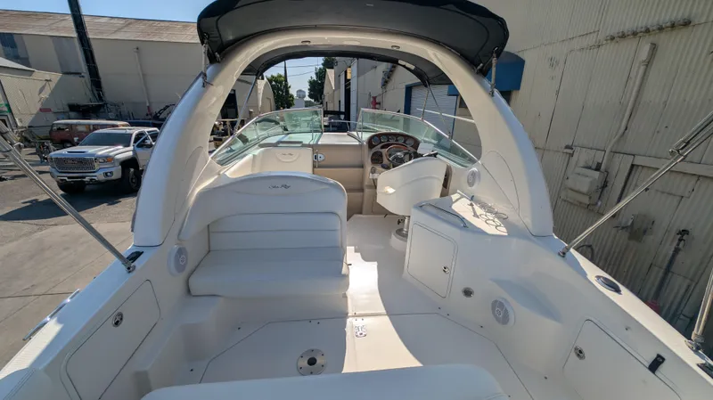 Slide: The Image of 2004 Sea Ray 280 Sundancer boat interior with seating and helm, docked outdoors. - 16