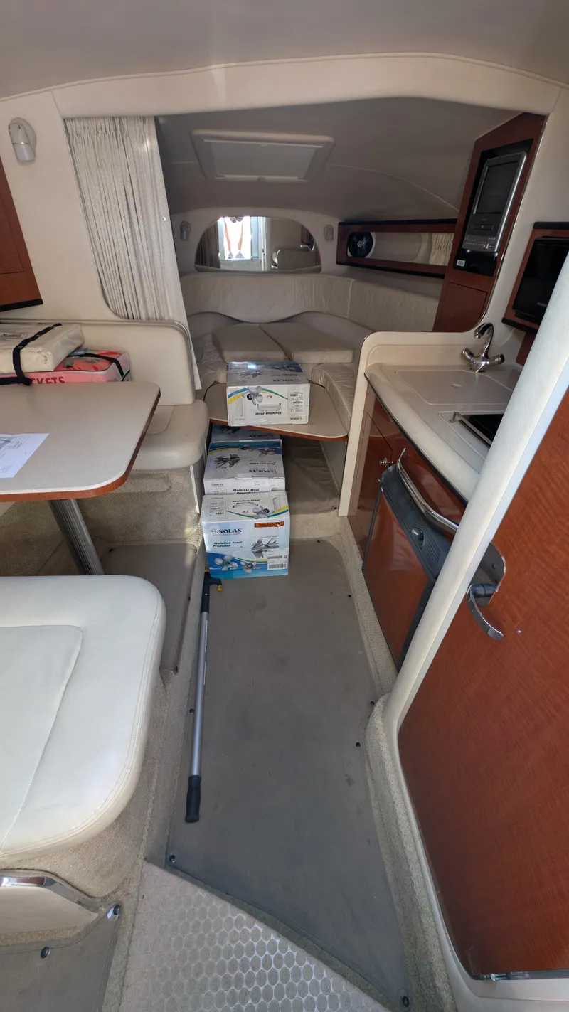 Slide: The Image of Interior of 2004 Sea Ray 280 Sundancer boat, featuring seating, table, and kitchenette. - 18