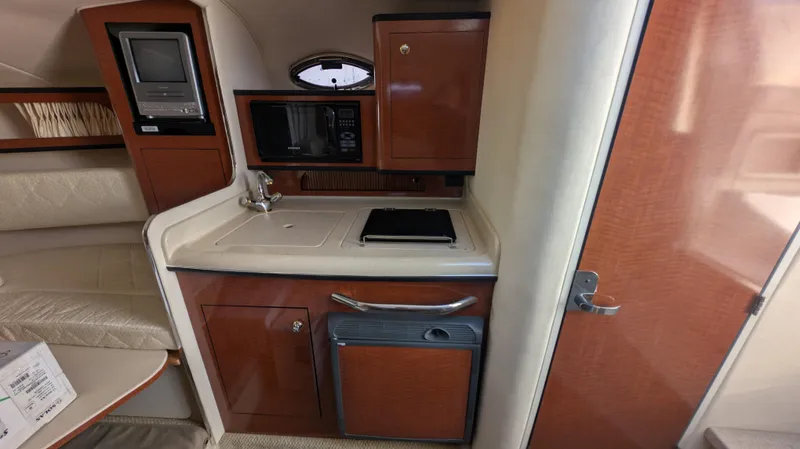 Slide: The Image of 2004 Sea Ray 280 Sundancer cabin kitchen with sink, microwave, and compact fridge. - 20