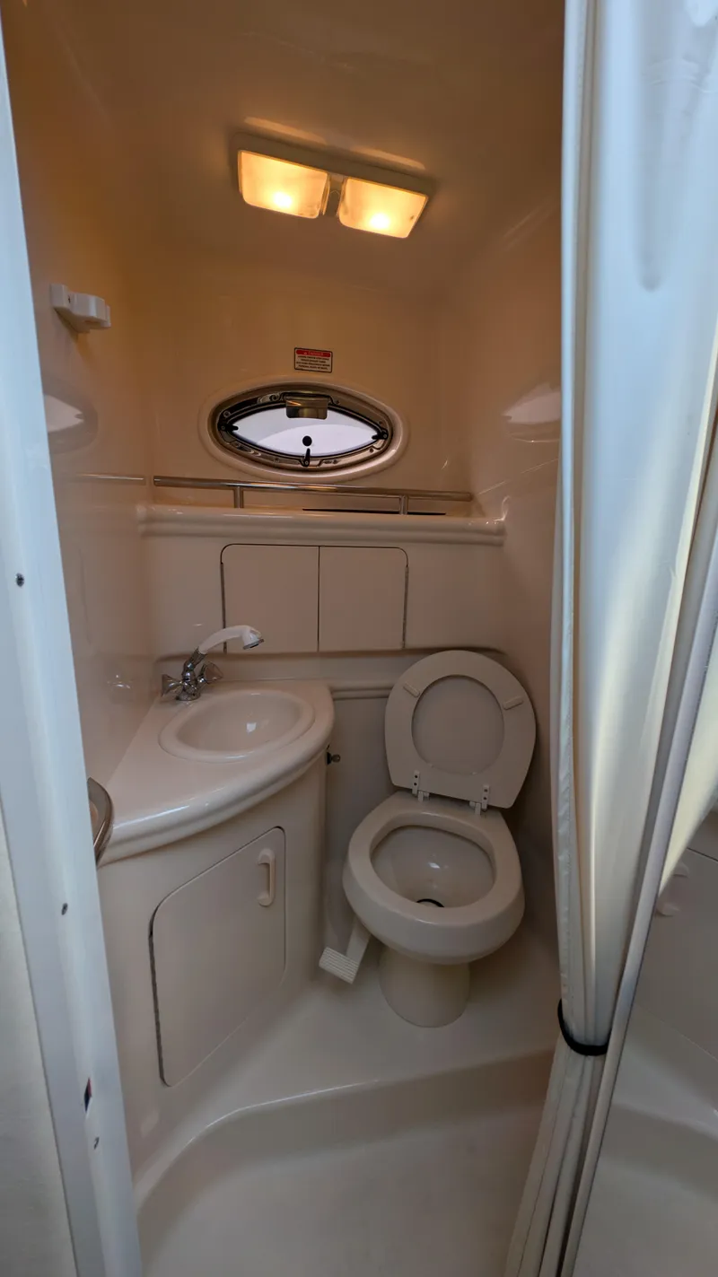 Slide: The Image of 2004 Sea Ray 280 Sundancer bathroom with sink, toilet, and porthole window. - 21