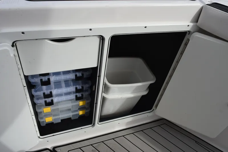 Slide: The Image of Storage compartments on a 2021 Yamaha Boats 255 FSH Sport E, featuring tackle boxes and a bin. - 15