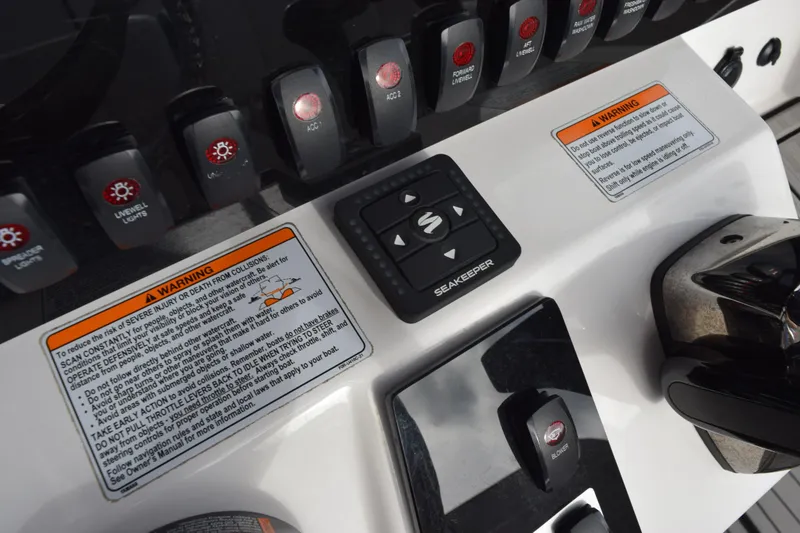 Slide: The Image of Control panel of 2021 Yamaha Boats 255 FSH Sport E with warning labels and Seakeeper controls. - 17
