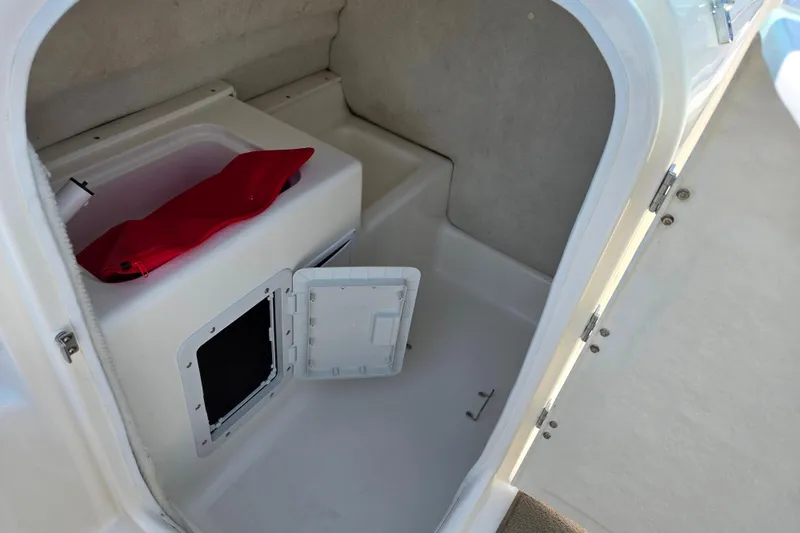 Slide: The Image of 2006 Glastron DX 235 boat interior storage compartment with open hatch and red bag. - 11