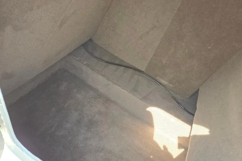 Slide: The Image of Interior storage compartment of a 2006 Glastron DX 235 boat, featuring carpeted walls. - 17