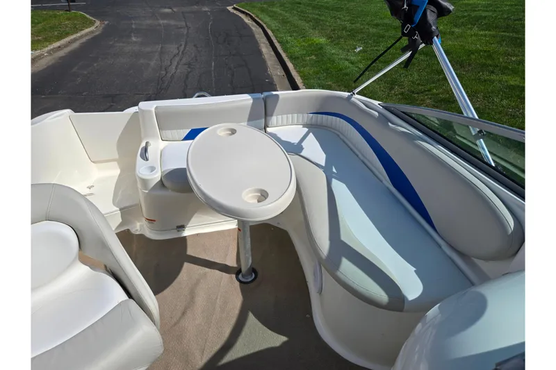 Slide: The Image of 2006 Glastron DX 235 boat interior with seating and table, featuring blue and white upholstery. - 23
