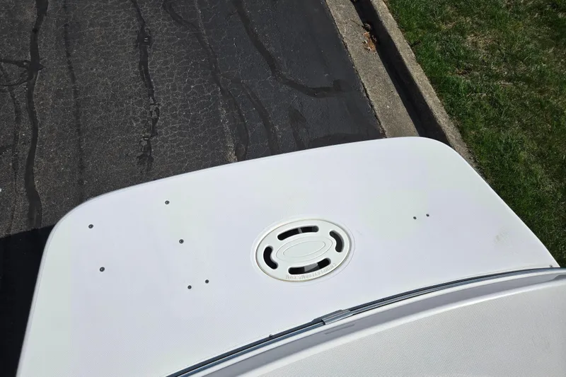 Slide: The Image of 2006 Glastron DX 235 boat deck with circular hatch, parked on asphalt. - 26