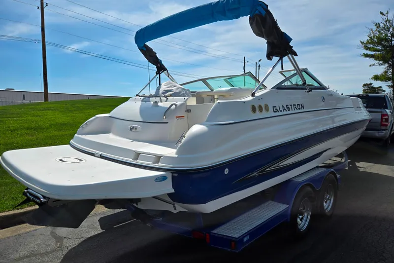 Slide: The Image of 2006 Glastron DX 235 boat on trailer, featuring blue and white design with a covered canopy. - 3