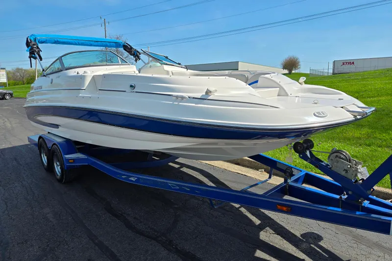 Slide: The Image of 2006 Glastron DX 235 boat on trailer, white and blue design, parked outdoors. - 5