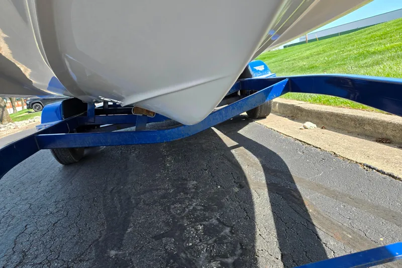 Slide: The Image of 2006 Glastron DX 235 boat on blue trailer, parked on asphalt near grass. - 7