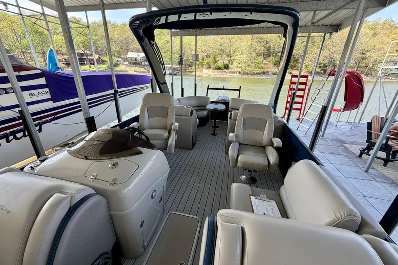 Slide: The Image of 2017 South Bay 725 RS pontoon boat interior with seating and helm, docked by a lake. - 7