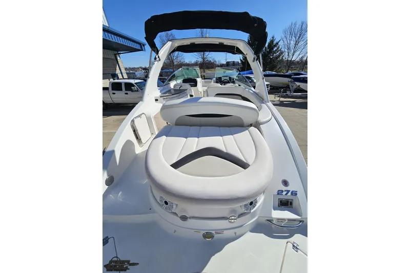 Slide: The Image of 2010 Chaparral 276 SSX boat with white seating and black canopy, docked outdoors. - 33