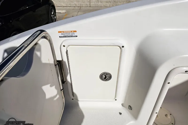 Slide: The Image of 2010 Chaparral 276 SSX boat interior with storage compartment and safety warning label. - 49