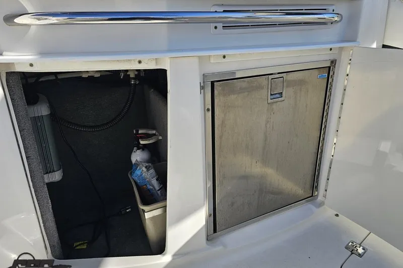 Slide: The Image of 2010 Chaparral 276 SSX boat storage compartment with stainless steel door and interior equipment. - 53